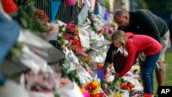 Mourners lay flowers on a wall at the Botanical Gardens in Christchurch, New Zealand, March 16, 2019. New Zealand's stricken residents reached out to Muslims in their neighborhoods and around the country Saturday, in a fierce determination to show kindness to a community in pain.