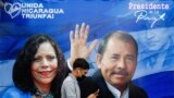 A man checks his phone while walking by a banner promoting Nicaraguan President Daniel Ortega 