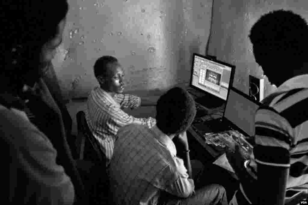 Shakuol, age 20, a genocide orphan, talks to clients while he edits a wedding video in his studio, Giporoso, Kigali, Rwanda, Nov. 20, 2013. (Hamada Elrasam for VOA)
