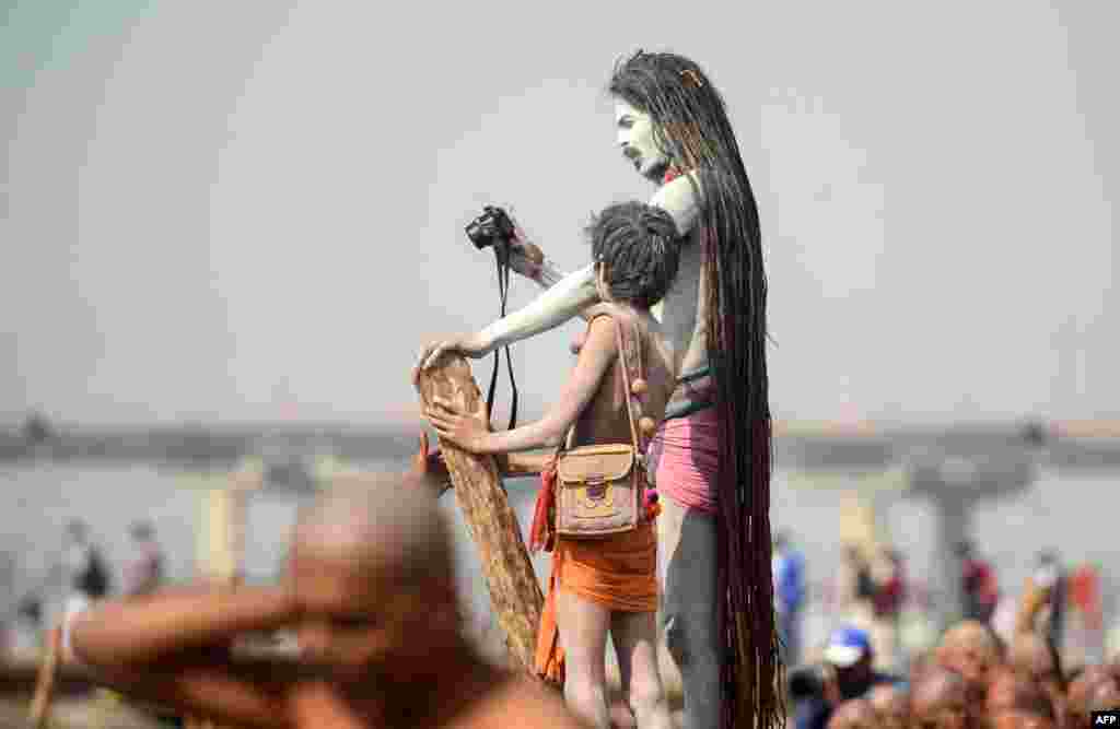 Indian Naga Sadhus (Hindu holy men) take photos as newly-initiated Naga Sadhus perform rituals on the banks of the Ganges River during the Kumbh Mela festival, in Allahabad.