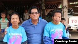 Im Chaem and her husband are pictured with pastor Christopher LaPel, middle, outside of her home in O'Angre village, Anlong Veng district, Oddar Meanchey province, Cambodia. (Courtesy photo of Pastor Touch Chanthou)