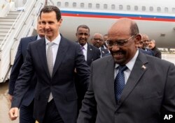 FILE - In this photo released by the Syrian official news agency SANA, Syrian President Bashar al-Assad, left, meets with Sudan's President Omar al-Bashir in Damascus, Syria, Dec. 16, 2018.