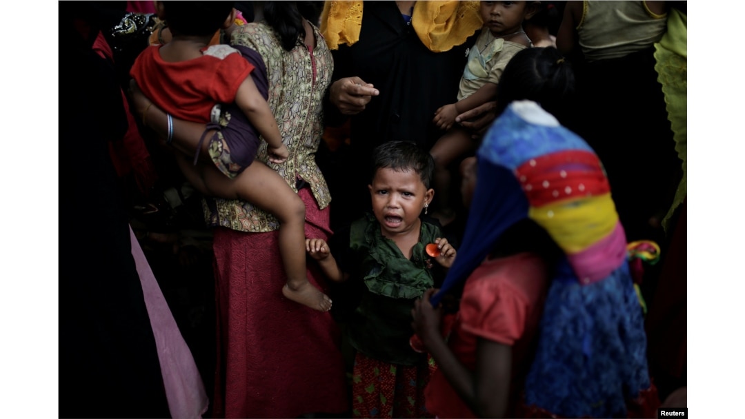 A baby cries as Rohingya refugees line up for a food supply distribution at the Kutupalong refugee camp near Cox's Bazar, Bangladesh Dec. 12, 2017.