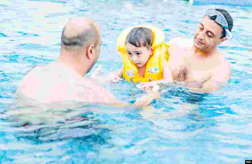 With the Black Sea tinted brown by the flooding Enguri River, a Georgian father give his son swimming lessons in the swimming pool of the Hotel Anaklia. (V. Undritz for VOA)