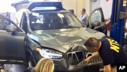 In this March 20, 2018, photo provided by the National Transportation Safety Board, investigators examine a driverless Uber SUV that fatally struck a woman in Tempe, Ariz. (National Transportation Safety Board via AP)