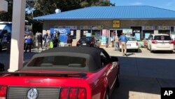 FILE - Media, at left, record people entering the KC Mart in Simpsonville, S.C., after it was announced the winning Mega Millions lottery ticket was purchased at the store, Oct. 24, 2018.