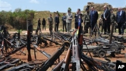 French President Francois Hollande, third right, and his Defense Minister Jean-Yves Le Drian, second right, inspect arms confiscated from ex-Seleka rebels and Anti-balaka militia by the French military of operation Sangaris, and displayed at a French mili