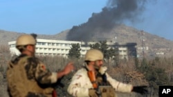 Afghan security personnel stand guard as black smoke rises from the Intercontinental Hotel, Jan. 21, 2018, after an attack in Kabul, Afghanistan.
