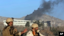 Afghan security personnel stand guard as black smoke rises from the Intercontinental Hotel, Jan. 21, 2018, after an attack in Kabul, Afghanistan. Gunmen stormed the hotel and set off a 12-hour gun battle with security forces that continued into Sunday morning, as frantic guests tried to escape from fourth- and fifth-floor windows.