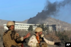 Afghan security personnel stand guard as black smoke rises from the Intercontinental Hotel, Jan. 21, 2018, after an attack in Kabul, Afghanistan. Gunmen stormed the hotel and set off a 12-hour gun battle with security forces that continued into Sunday.