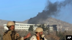 아프간 보안군이 반군의 공격으로 검은 연기가 솟아오르는 인터콘티넨탈 호텔 앞을 지키고 있다.