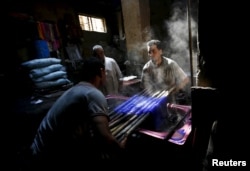 Mohamed Mostafa, 35, and Hisham Aly, 37, work at a dye workshop in old Cairo, Egypt, March 17, 2016.