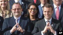 International Olympic Committee Evaluation Commission Chair Patrick Baumann, left, and new French President Emmanuel Macron make a singe representing the logo of Paris 2024 bid as they pose during a group photo at the Elysee palace in Paris, France, May 16, 2017.