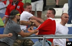 FILE - Russian supporters attack an England fan at the end of the Euro 2016 Group B soccer match between England and Russia, at the Velodrome stadium in Marseille, France, June 11, 2016. The violence raised serious concerns about Russian football hooliganism.