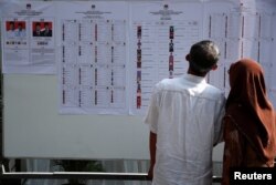 People look at a list of electoral candidates during elections in Jakarta, Indonesia, April 17, 2019.