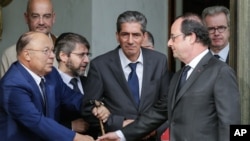 French President Francois Hollande shakes hands with Paris Mosque rector Dalil Boubakeur, left, after a meeting with religious representatives at the Elysee Palace in Paris, following yesterday attack at a church in Normandy, July 27, 2016.