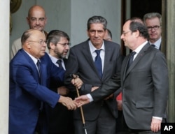 FILE - French President Francois Hollande shakes hands with Paris Mosque rector Dalil Boubakeur, left, after a meeting with religious representatives in Paris, July 27, 2016. Hollande said the excesses of U.S. presidential candidate Donald Trump "make you want to retch."