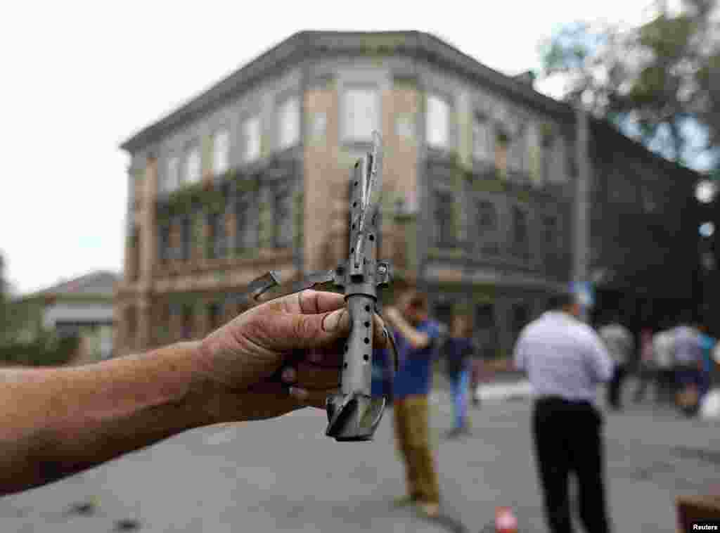 A man shows a piece of used weaponry at the site of fighting in Maruipol, Ukraine, June 13, 2014.
