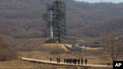 FILE - A group of journalists walk down a road in front of North Korea's Unha-3 rocket at the Sohae Satellite Station in Tongchang-ri, North Korea, April 8, 2012.