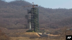 FILE - A group of journalists walk down a road in front of North Korea's Unha-3 rocket at the Sohae Satellite Station in Tongchang-ri, North Korea, April 8, 2012.