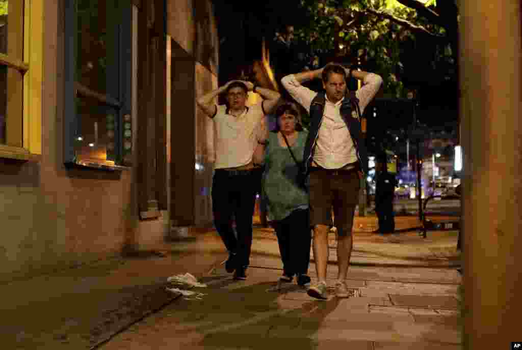 Personas que estaban dentro de la zona atacada por terroristas en el área del Puente de Londres el sábado por la noche, salen del cordón policial. Junio 3, 2017.