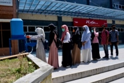 Sejumlah mahasiswi mencuci tangan di tengah pandemi virus corona sebelum mengikuti ujian masuk perguruan tinggi di Banda Aceh pada 5 Juli 2020. (Foto: AFP/Chaideer Mahyuddin)