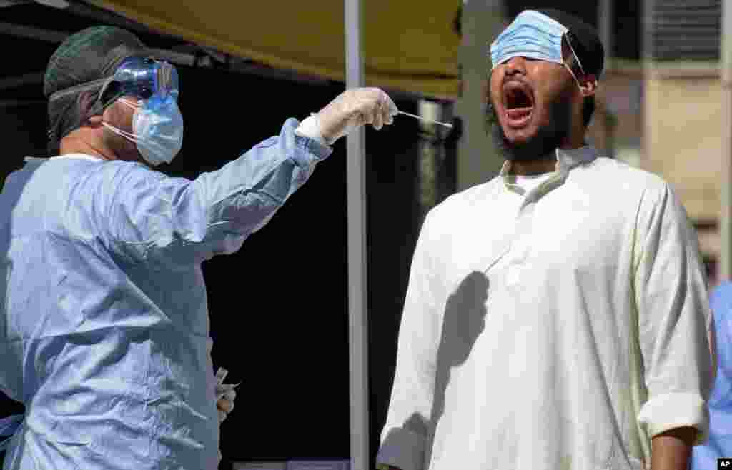 A member of the Bangladeshi immigrant community, right, has a swab being taken to test for COVID-19 outside a health care center in Rome.