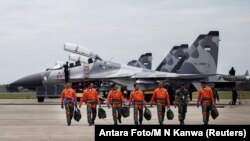 FILE - Indonesian Air Force Sukhoi fighter pilots and crew walk across the tarmac at the Hang Nadim Airport after training for an upcoming military exercise, Oct. 3, 2016.