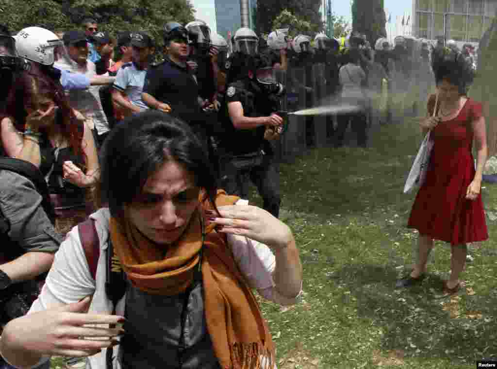A Turkish riot policeman uses tear gas as people protest against the destruction of trees in a park brought about by a pedestrian project, in Taksim Square in central Istanbul, May 28, 2013.