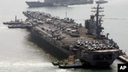 FILE - The USS Ronald Reagan anchors as a U.S. Aegis combat vessel passes at Busan port for joint military exercises in Busan, South Korea, March 22, 2007. The Reagan is now part of an annual bilateral training exercise with Japanese naval forces.
