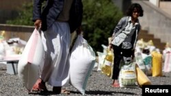 A young woman carries food received from a local charity during the holy month of Ramadan in Sanaa, Yemen, May 29, 2017. 