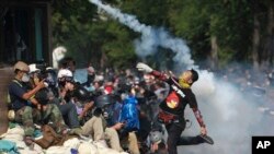 Seorang demonstran anti-pemerintah melemparkan kembali gas air mata yang ditembakkan oleh polisi anti huru-hara di Bangkok (2/12). (AP/Wason Wanichakom)