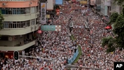 Des manifestants défilent dans une rue du centre-ville pour protester contre la loi sur l'extradition à Hong Kong le dimanche 9 juin 2019. (AP Photo / Vincent Yu)