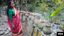 A woman in Chandipur village in southwest Bangladesh shows the pumpkins she grew in her "vertical garden." (Photo: A. Yee for VOA)