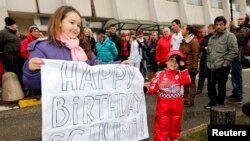 FILE - Kids celebrate with a placard the 45th birthday of seven-times former Formula One world champion Michael Schumacher in front of the CHU hospital emergency unit in Grenoble, French Alps, where Michael Schumacher is hospitalized, Jan. 3, 2014. 