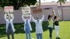 Los doctores Franklyn Rocha y Claudia Alvarez protrestan por las condiciones de los inmigrantes en un centro de detención en el condado de Broward. 