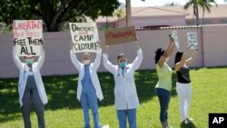 Los doctores Franklyn Rocha y Claudia Alvarez protrestan por las condiciones de los inmigrantes en un centro de detención en el condado de Broward. 