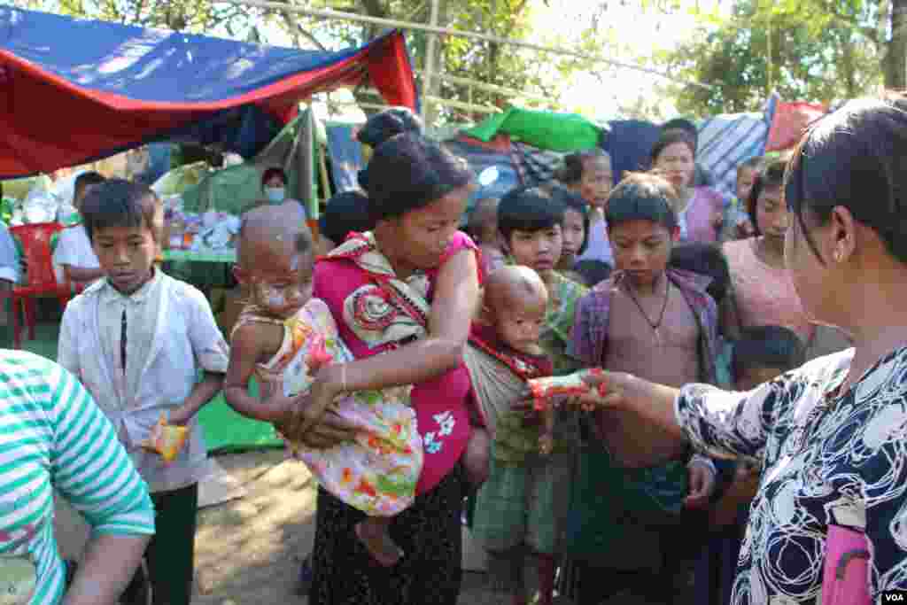 ဝါးတောင် စစ်ရှောင်စခန်းရှိ ကလေးငယ်များကို မုန့်ဝေငှနေသူတဦး။