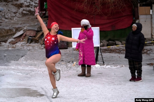 People in winter clothing watch as Yu Xiaofeng pose for a photo before jumping into the freezing water of the Songhua River, January 7, 2025. (AP Photo/Andy Wong)