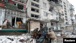 Service members of pro-Russian troops gather around a fire outside a residential building which was damaged during Ukraine-Russia conflict in Volnovakha