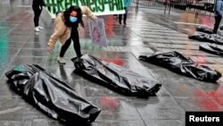 Pengunjuk rasa di Manhattan, New York, beraksi menggunakan kantong jenazah yang mewakili korban tewas corona, 1 Mei 2020. (Foto: Reuters)