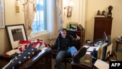 FILE - Richard Barnett, a supporter of President Donald Trump sits inside the office of then-U.S. Speaker of the House Nancy Pelosi during the U.S. Capitol riot, in Washington, Jan. 6, 2021.