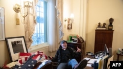 Richard Barnett, a supporter of President Donald Trump sits inside the office of US Speaker of the House Nancy Pelosi as he protests inside the U.S. Capitol in Washington, D.C., Jan. 6, 2021.
