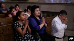 Parishioners Rosa Romero, center, and Jesus Romero, right, pray at St. Peter the Apostle Catholic Church in Reading, Pa., on June 9, 2024.