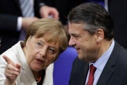 FILE - German Chancellor Angela Merkel talks to then-outgoing Foreign Minister Sigmar Gabriel in Germany's parliament in Berlin, March 14, 2018.