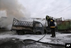 Firefighters spray a truck after a government airstrike in the city of Idlib, Syria, Feb. 11, 2020.