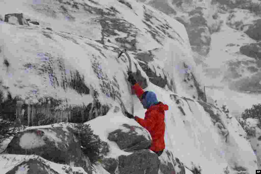 An ice climber makes his way up a wall during a snow storm on Donner Summit, Nov. 20, 2024, near Soda Springs, California.