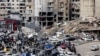 People gather as vehicles drive near damaged buildings, in Beirut's southern suburbs, after a ceasefire between Israel and Hezbollah took effect, Lebanon, Nov. 27, 2024. 