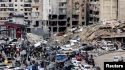 People gather as vehicles drive near damaged buildings, in Beirut's southern suburbs, after a ceasefire between Israel and Hezbollah took effect, Lebanon Nov. 27, 2024. 