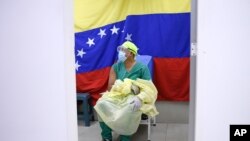 Con el telón de fondo de una bandera nacional, un médico espera recibir una dosis de la vacuna rusa COVID-19 Sputnik V en el hospital público Ana Francisca Pérez de León II en Caracas, el 19 de febrero de 2021.